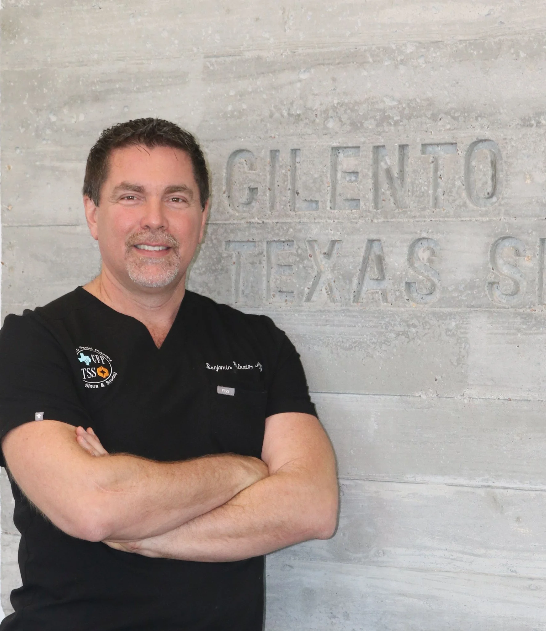 Dr. Ben Cilento, ENT surgeon, posing with arms crossed in front of Texas Sinus and Snoring signage